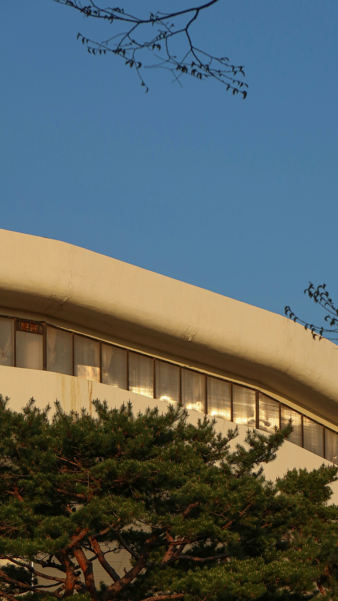 beige concrete building near green trees under blue sky during daytime